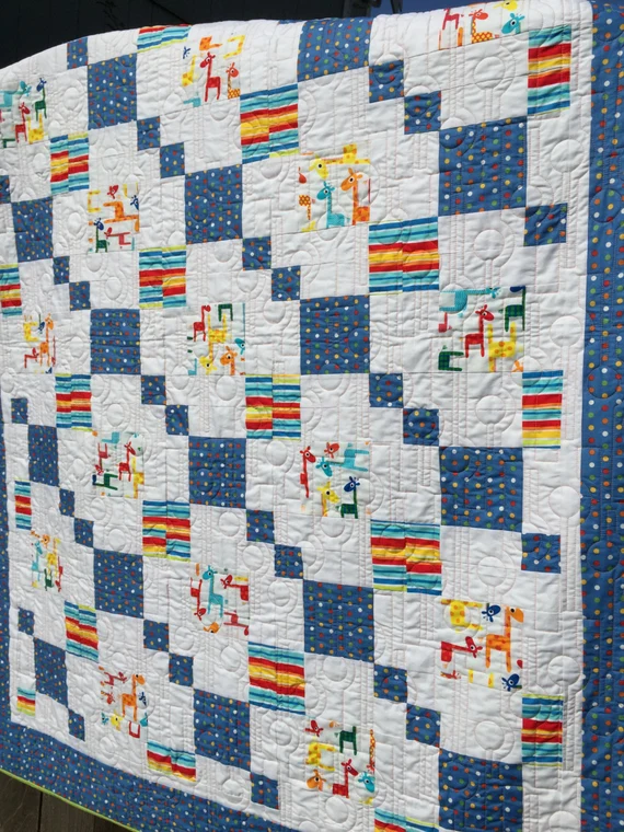 Patchwork quilt with blue and white squares featuring colorful giraffe and animal print fabric, playful childlike mood